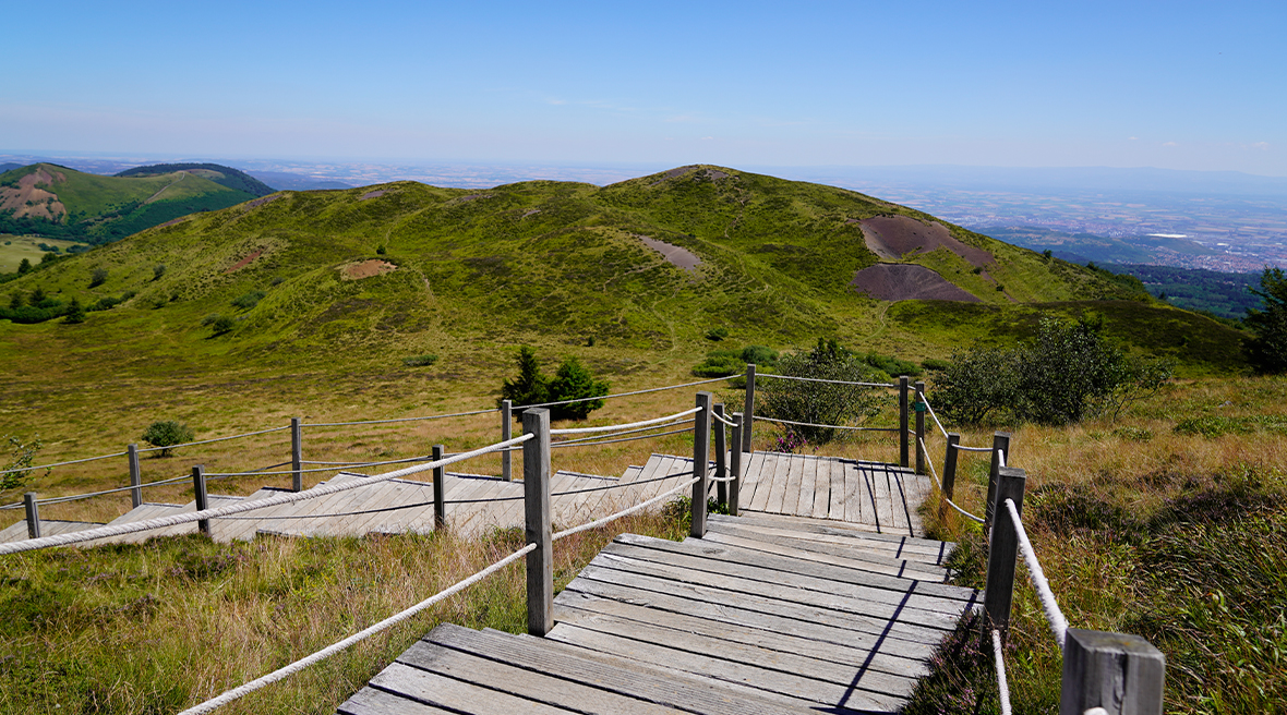 wooden steps leading around a green landscape with lots of hills and valleys
